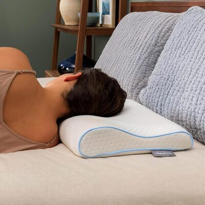 Woman lying on bed using supportive neck pillow